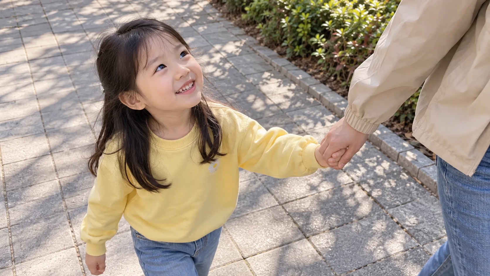 엄마 손을 잡고 걸으며 올려다보고 웃는 아이